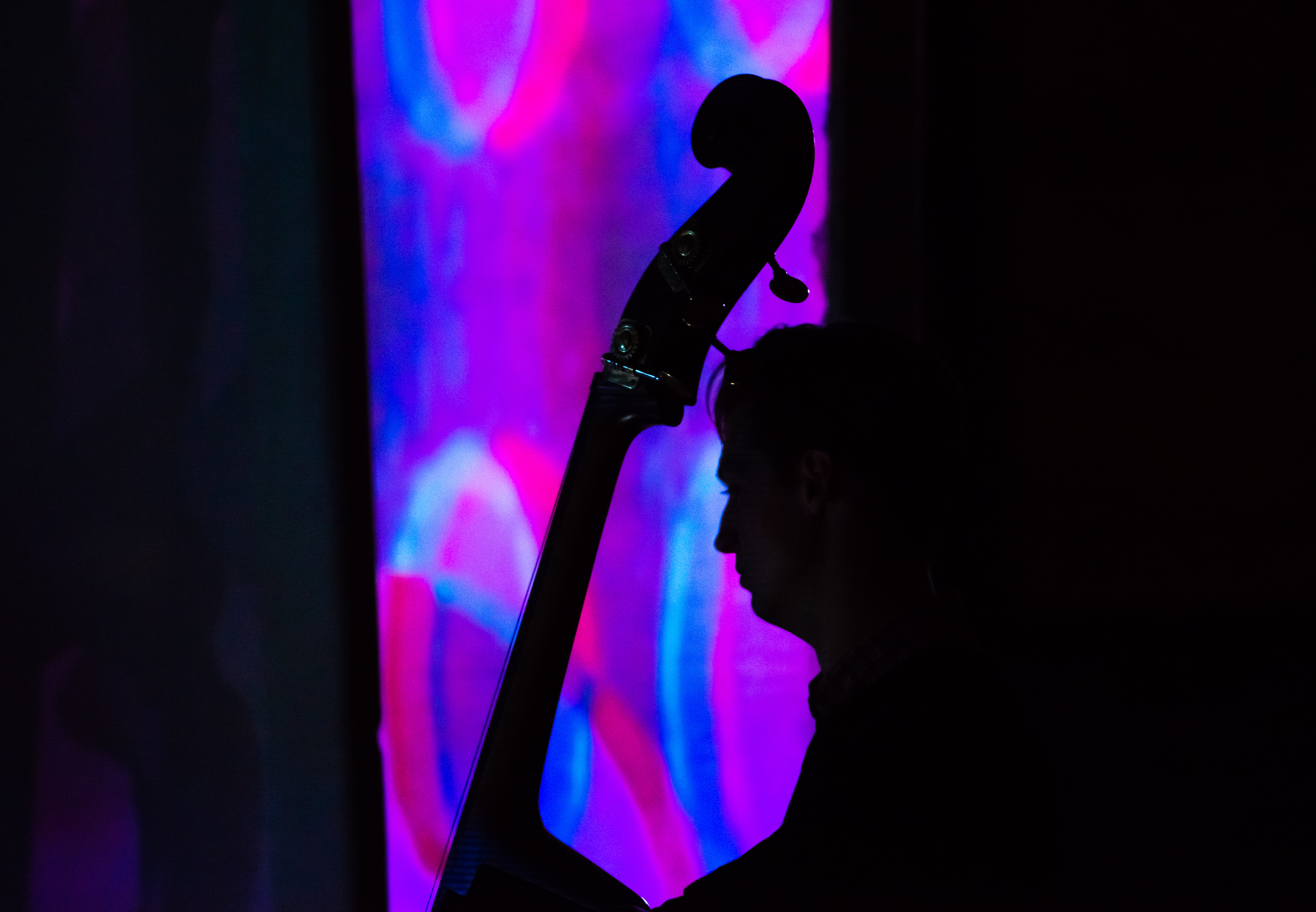 Student with cello backlit by purple and blue projection