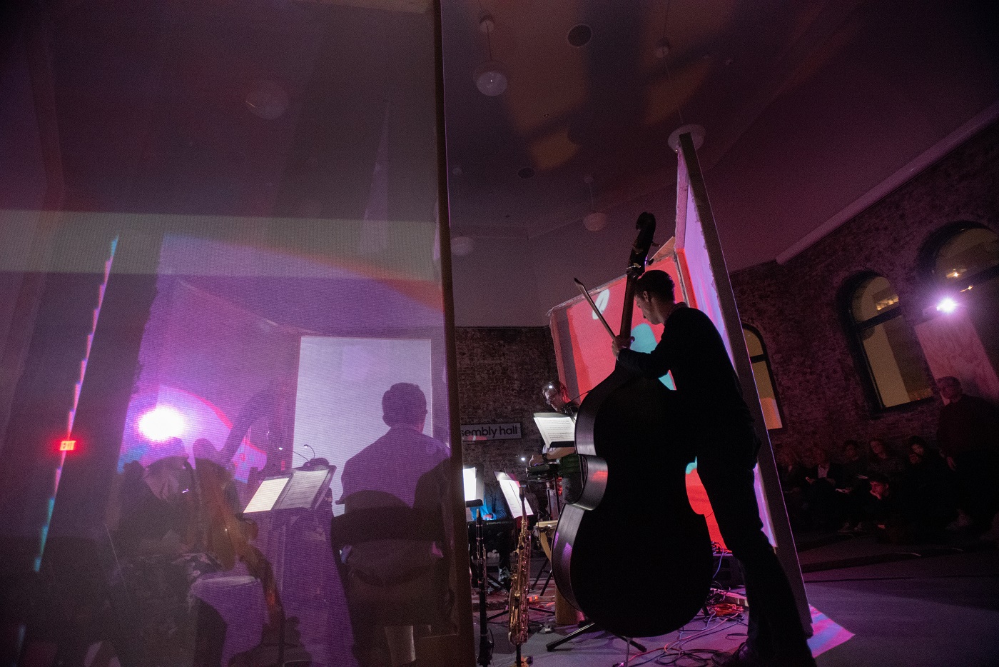 Student with cello backlit by purple and blue projection