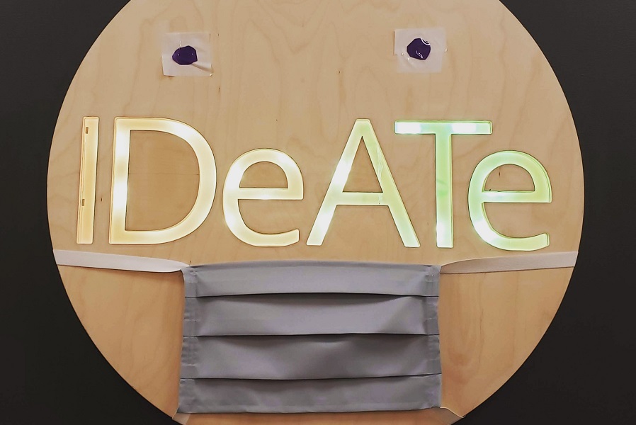 Wooden IDeATe sign in Hunt Library wearing a COVID mask
