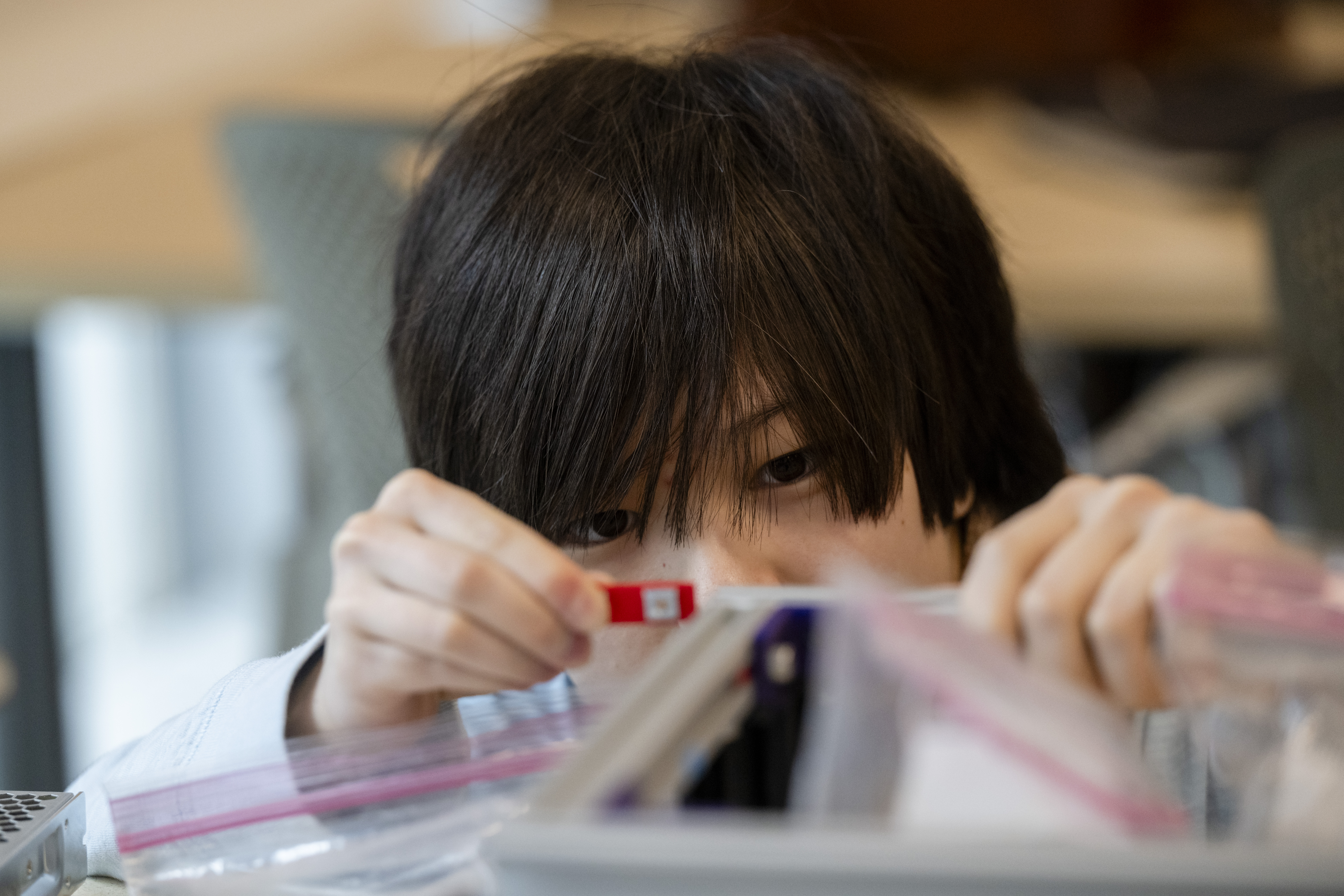 Close-up image of a student, Sachi Onishi, constructing a robotic loom