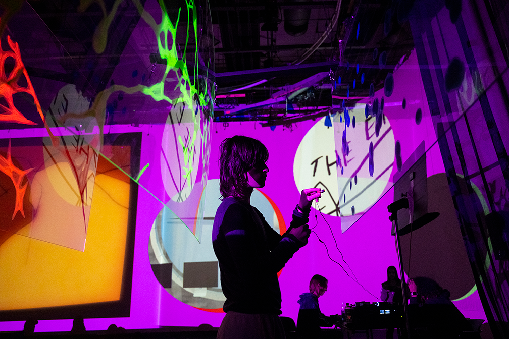 a student stands in the middle of the image, backlit by a pink screen