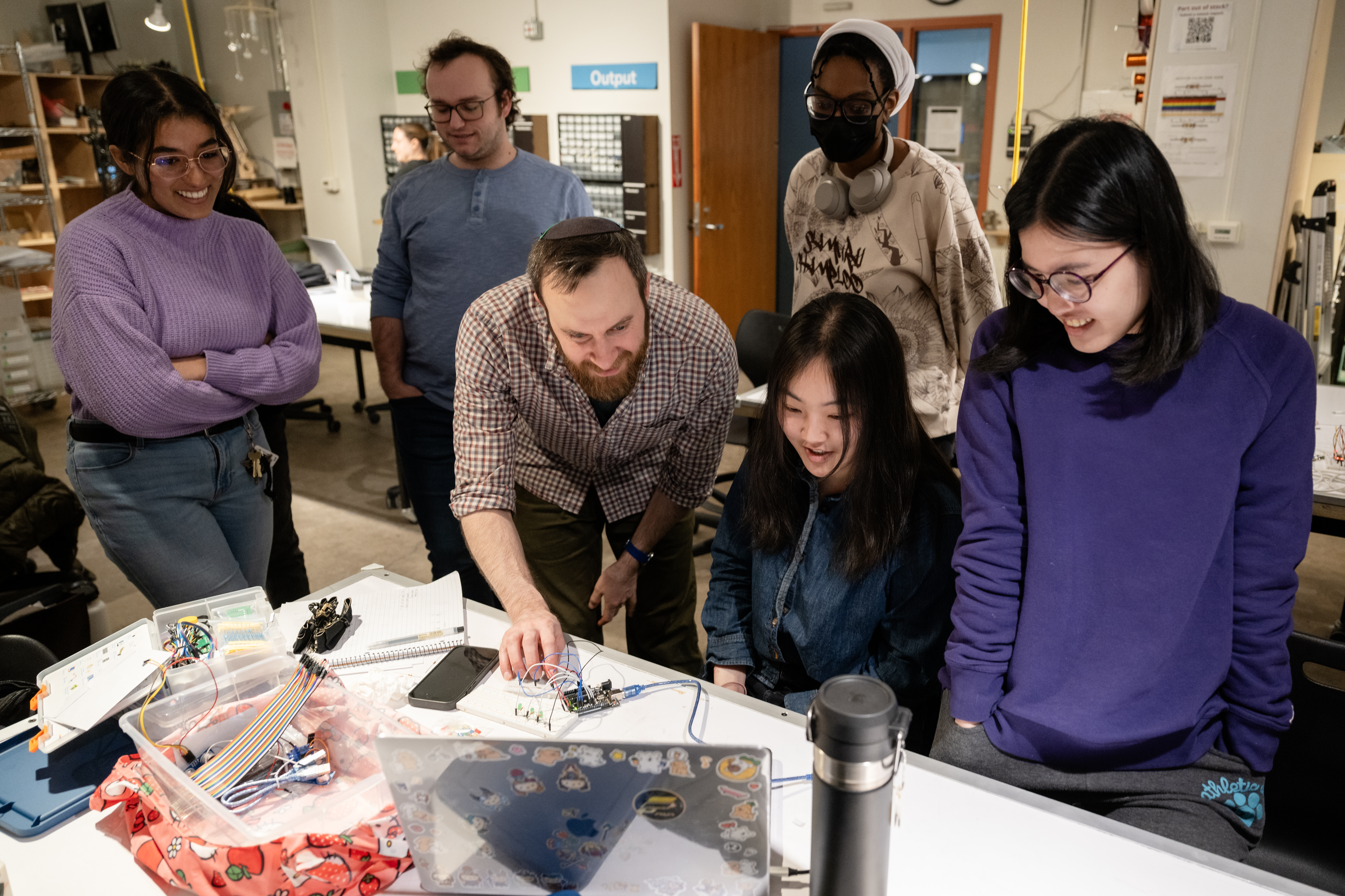 a professor surrounded by five students teaches a physical computing lesson
