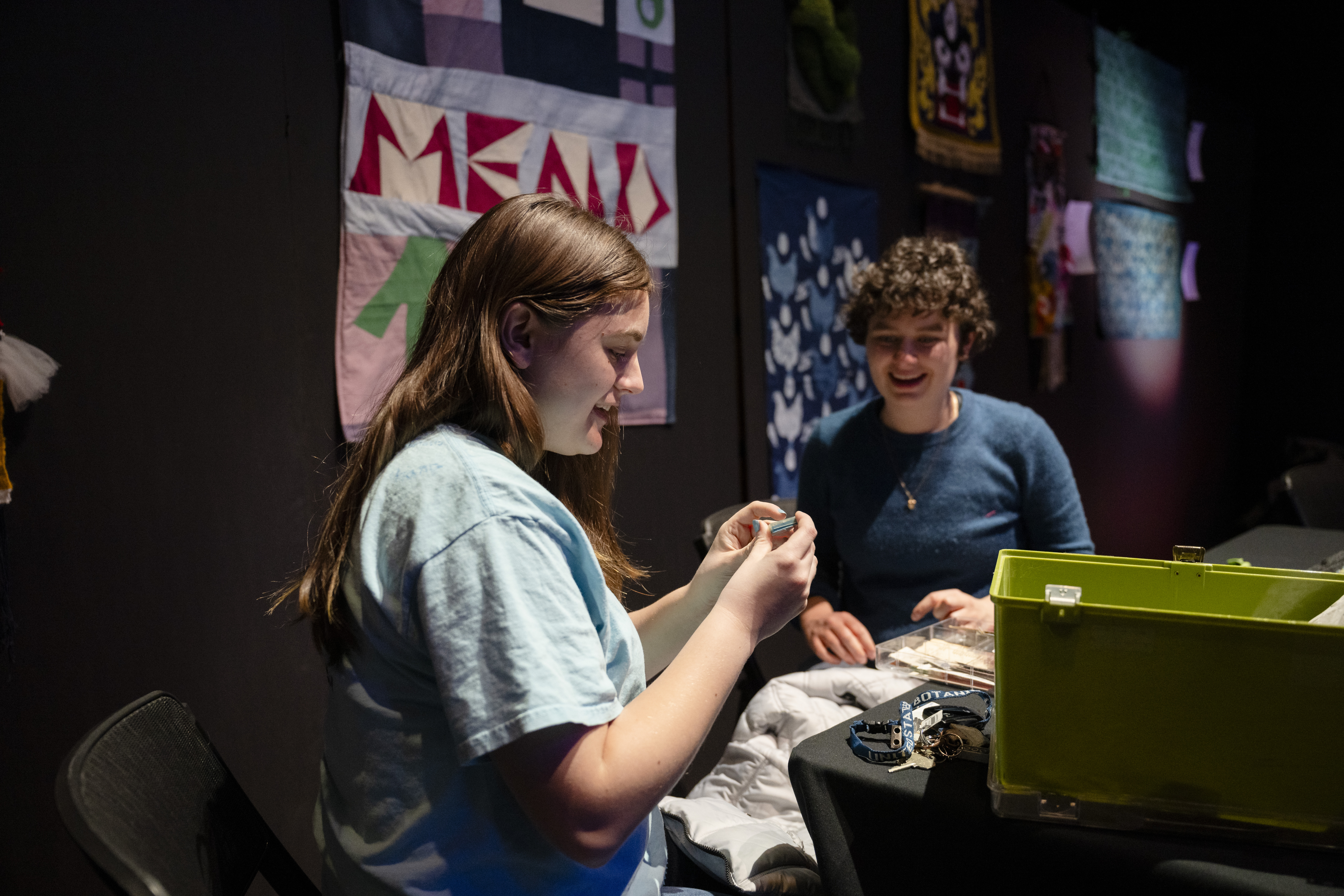 two students mend a jacket in the studio theater