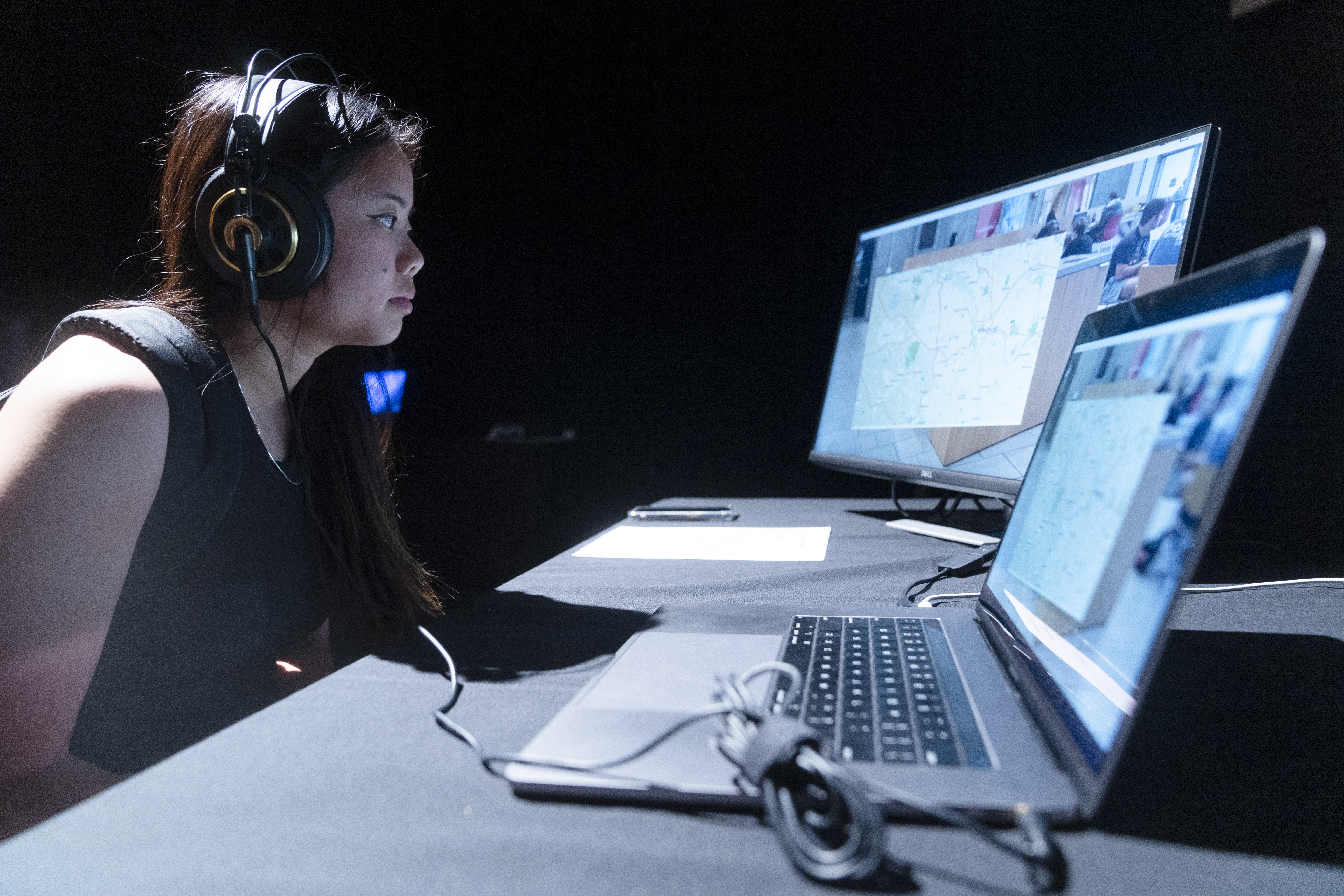 a student wearing headphones looks at a video on two computer screens