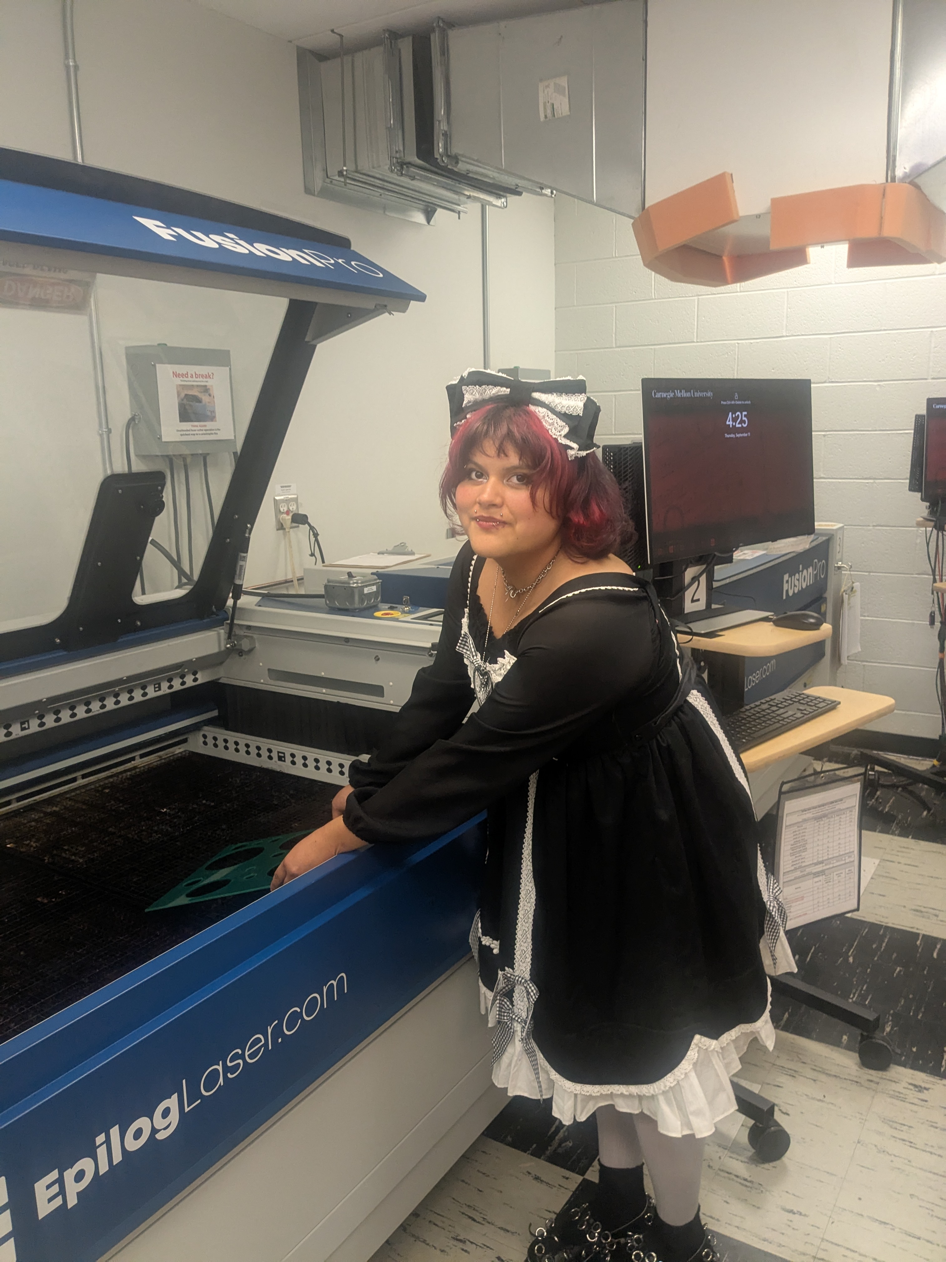 a student in a black and white dress poses by an epilog laser machine