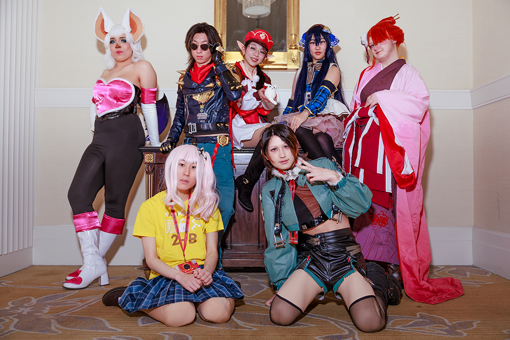 Seven cosplayers dressed as various anime characters, including brightly colored wigs and clothes, pose for the camera
